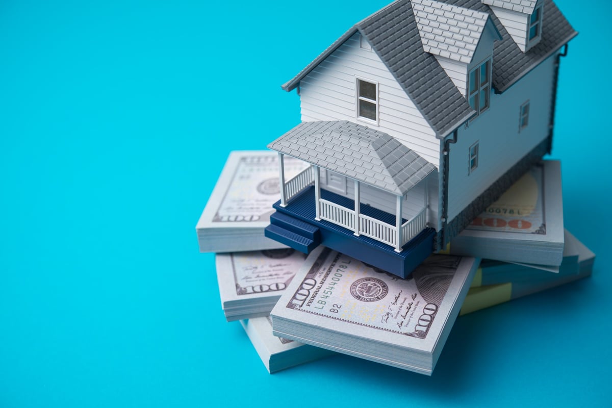 House model on heap US dollar banknotes showing home equity concept